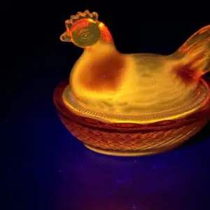 Glass chicken figurine illuminated against dark background